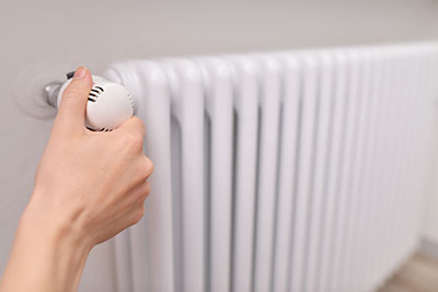 Closeup on woman’s hand adjusting thermostat valve. Hand regulat