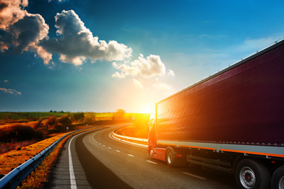 Arriving white truck on the road in a rural landscape at sunset
